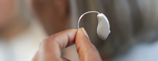Close-up image of hand holding a hearing aid